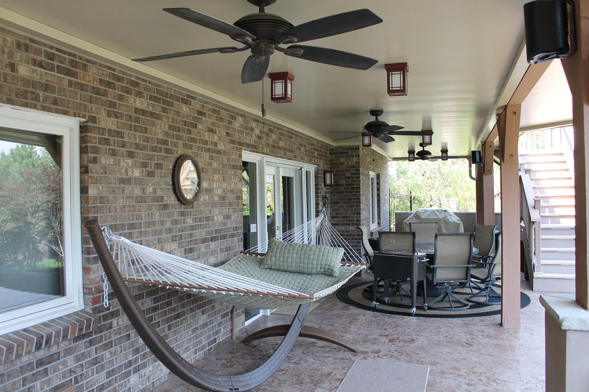Covered patio with brick wall, hammock, dining set, and ceiling fans.