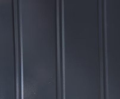 Dark gray corrugated metal siding with vertical grooves.