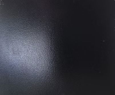 Black, textured surface with some highlights and shadows.