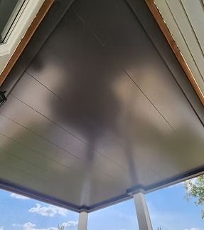 Dark gray porch ceiling with wooden trim, reflecting the sky.