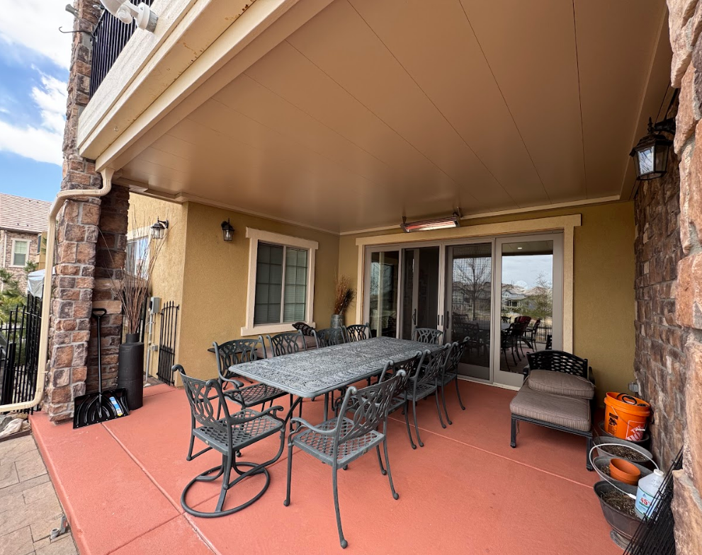 Covered patio with a table and chairs, sliding glass door, and brick columns.