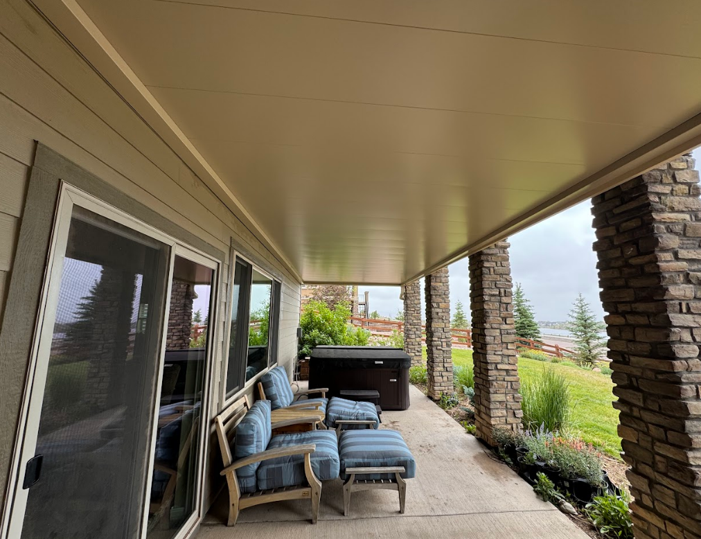 Covered patio with seating, hot tub, and stone columns.