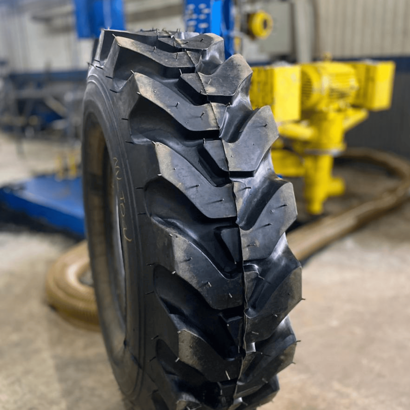 Pneu de trator preto com sulcos profundos, para uso interno.