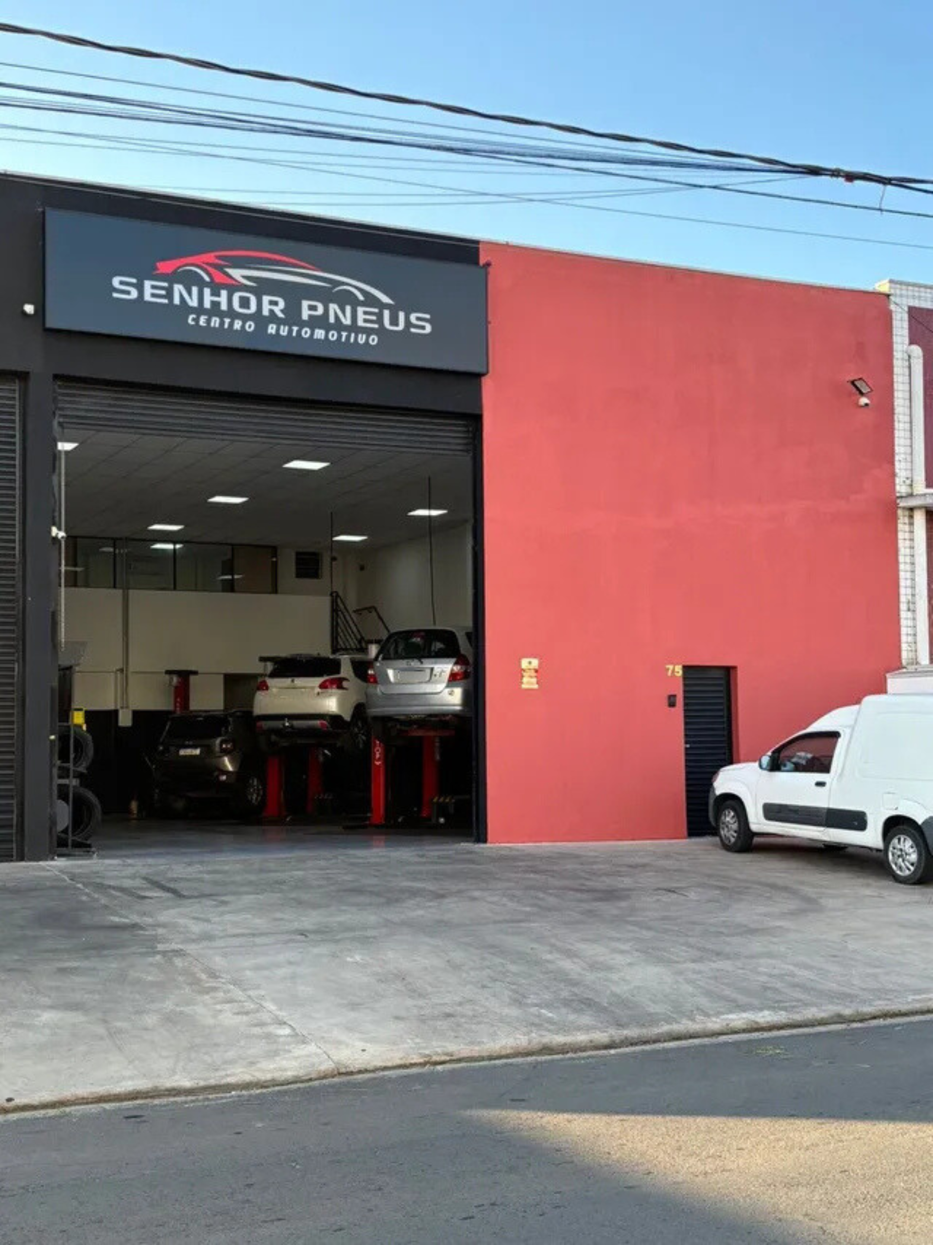 Pneus pendurados em um suporte em uma fábrica, provavelmente para inspeção ou processamento.