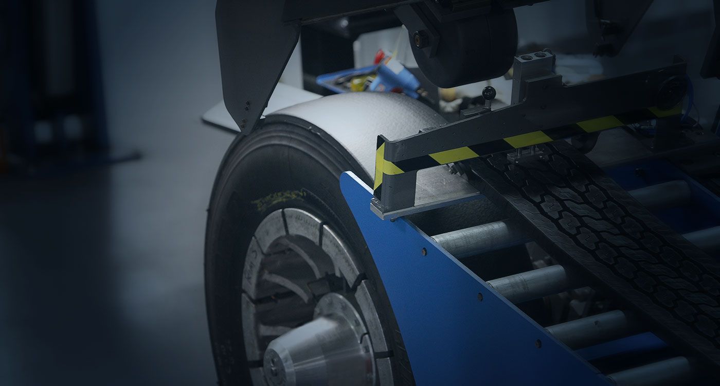 Imagem em close-up de um pneu sendo montado em um aro por uma máquina em uma oficina.