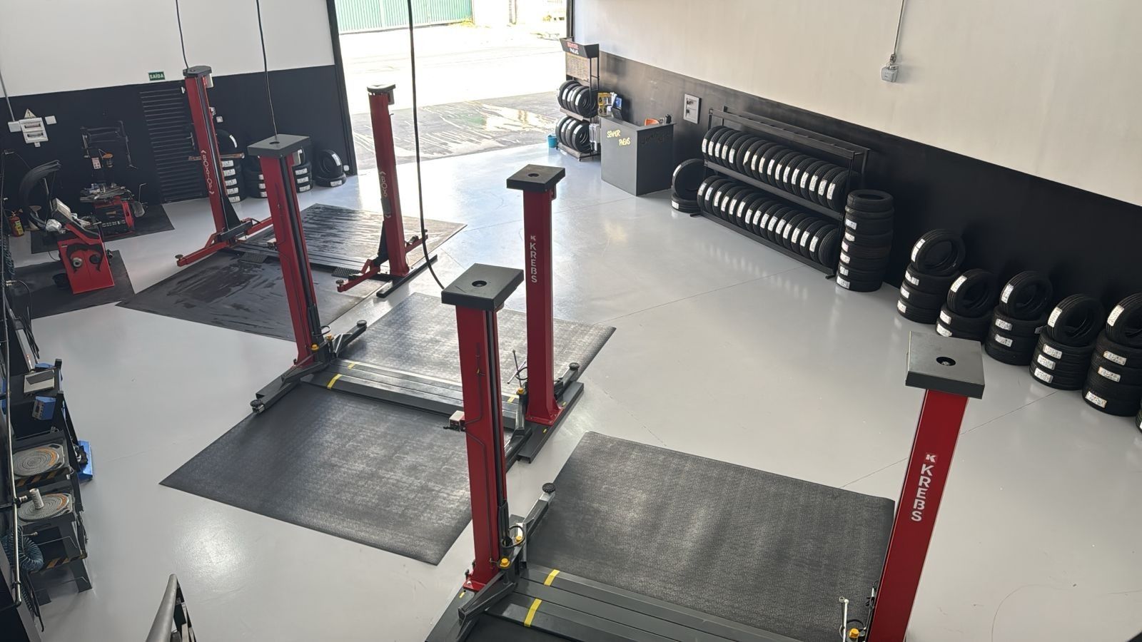 Pessoa utilizando uma ferramenta elétrica para remover um pneu de um caminhão; ao ar livre, durante o dia.