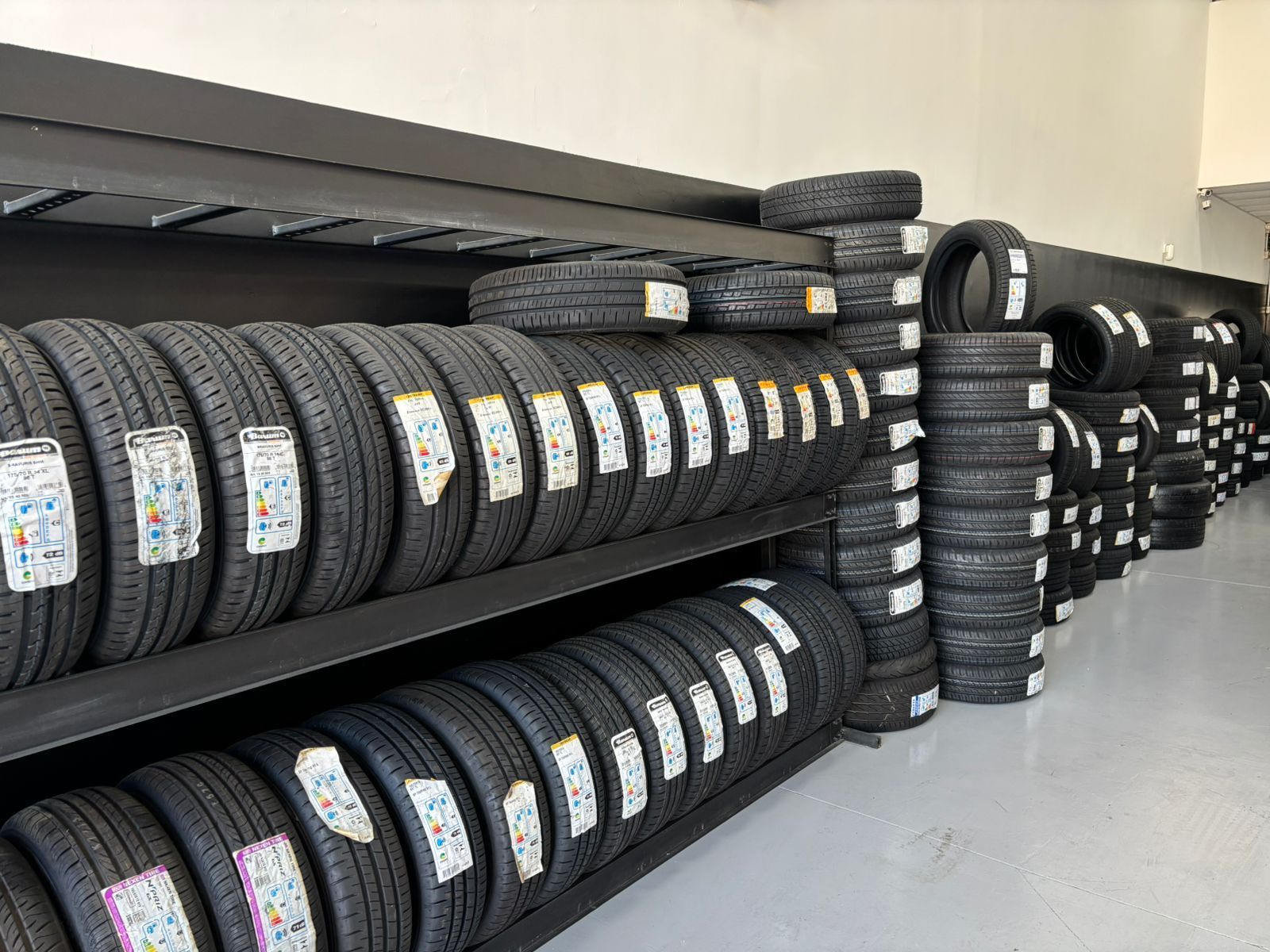 Oficina mecânica com carros em elevadores e mecânicos trabalhando. A marca Bridgestone está visível.