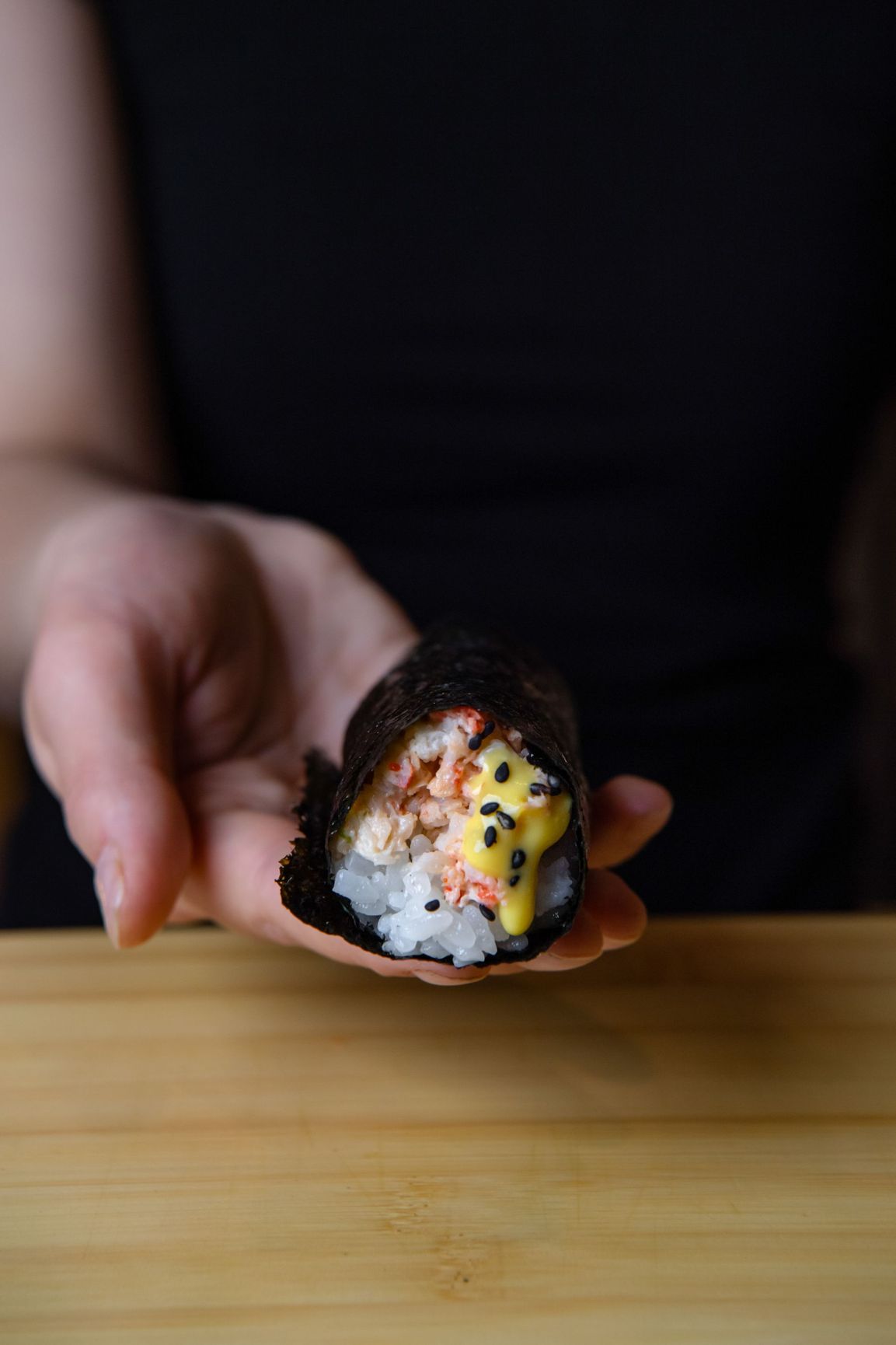 A person is holding a piece of sushi in their hand