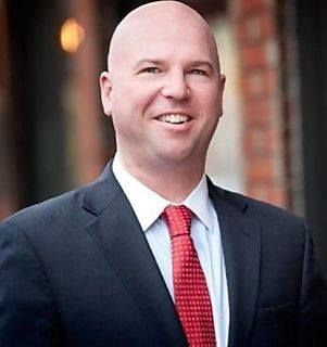 Attorney MacLachlan in a suit and tie is smiling for the camera.