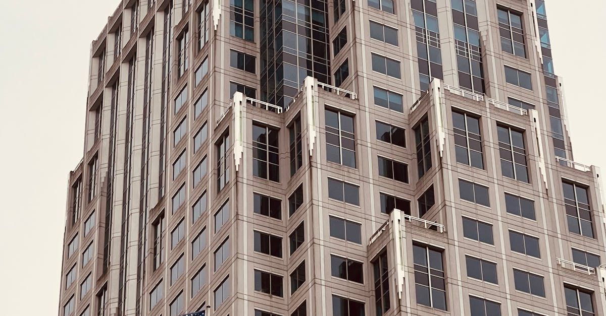 A tall building with a lot of windows is against a white sky.