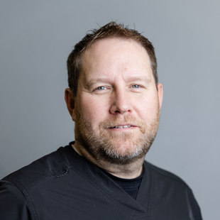 Man with short brown hair and beard, wearing a black shirt, looking at the viewer.