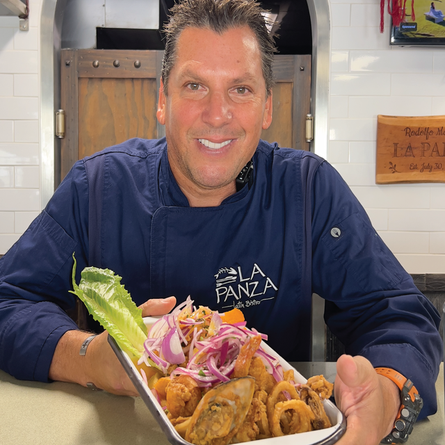 A man in a chef 's uniform is holding a plate of food