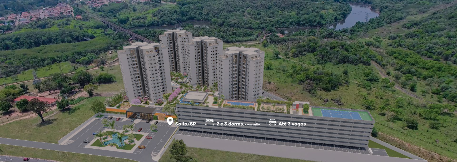 Vista aérea de prédios de apartamentos e estacionamento ao lado de uma área florestal e um rio.