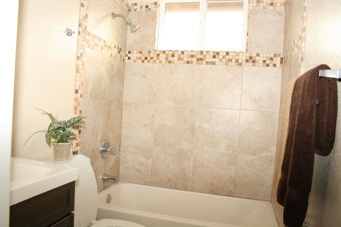 A bathroom with a tub , toilet , sink and window.