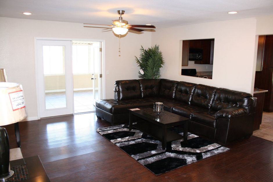 Living room with a dark leather sectional, coffee table, and sliding glass doors.