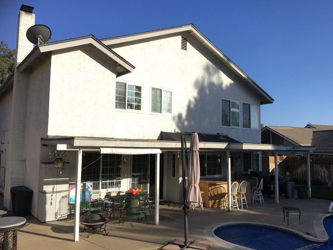 A white house with a patio and a pool in front of it