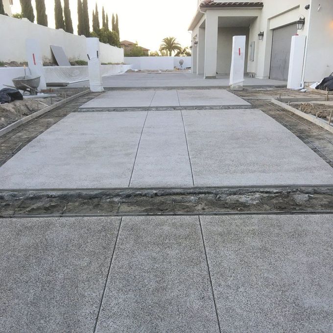 A concrete driveway is being built in front of a house