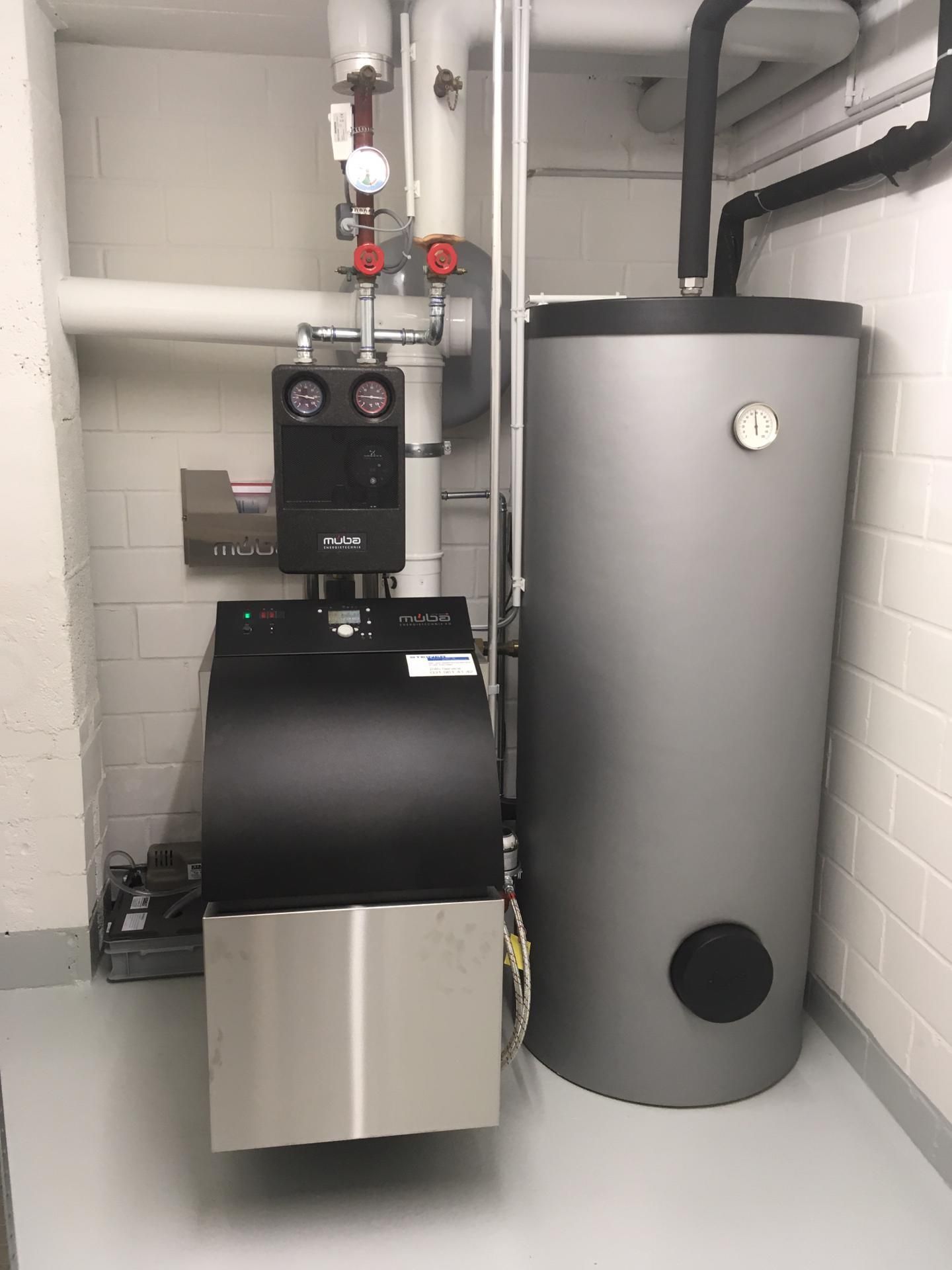 Eine Heizung und ein Wassertank stehen in einem Raum nebeneinander .