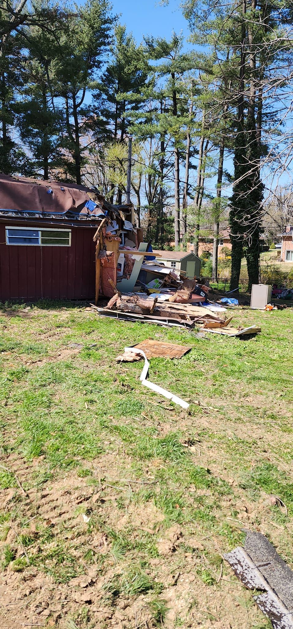 A shed is sitting in the middle of a grassy field next to a house.