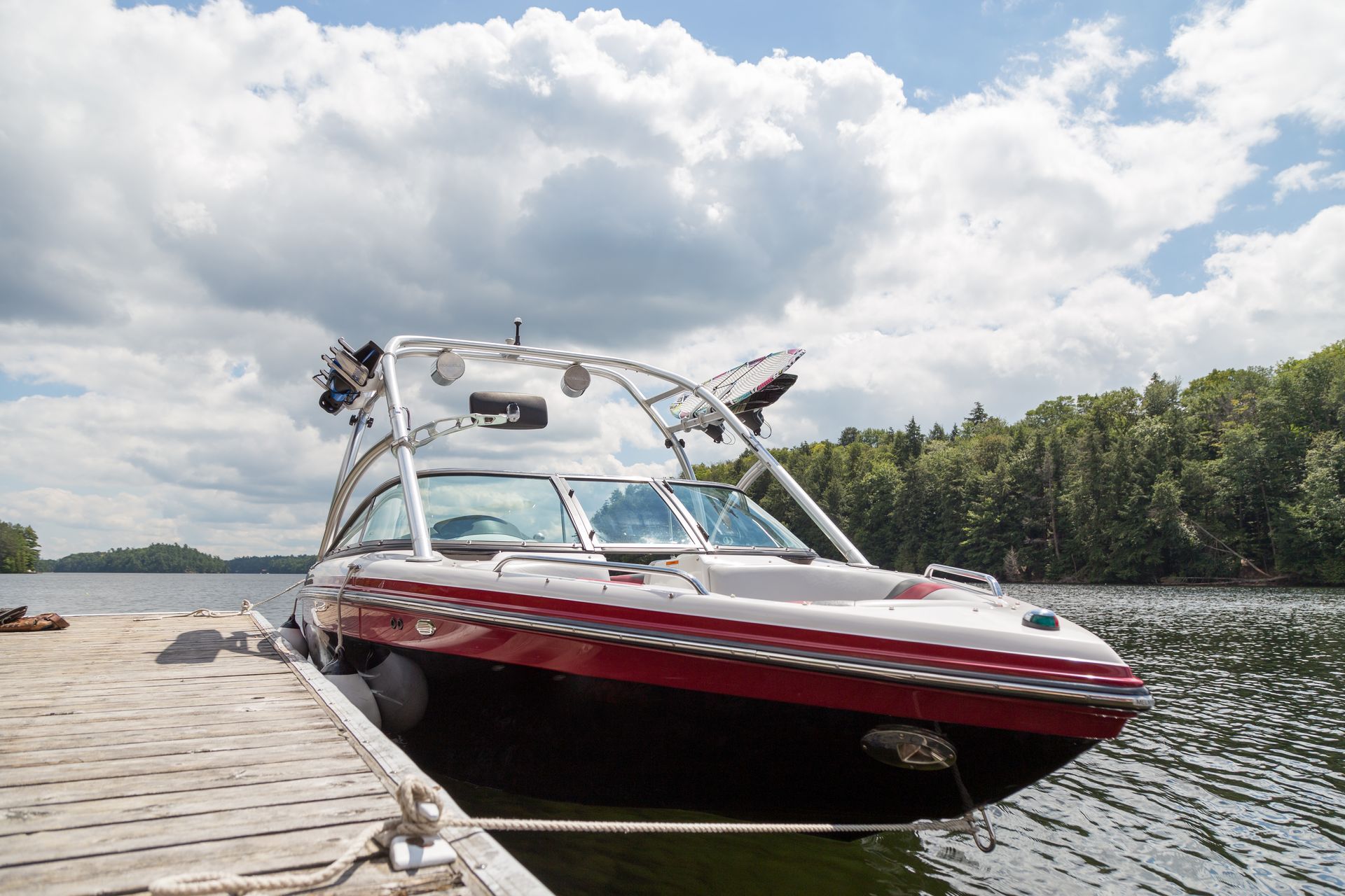A red and white boat is docked at a dock on a lake.