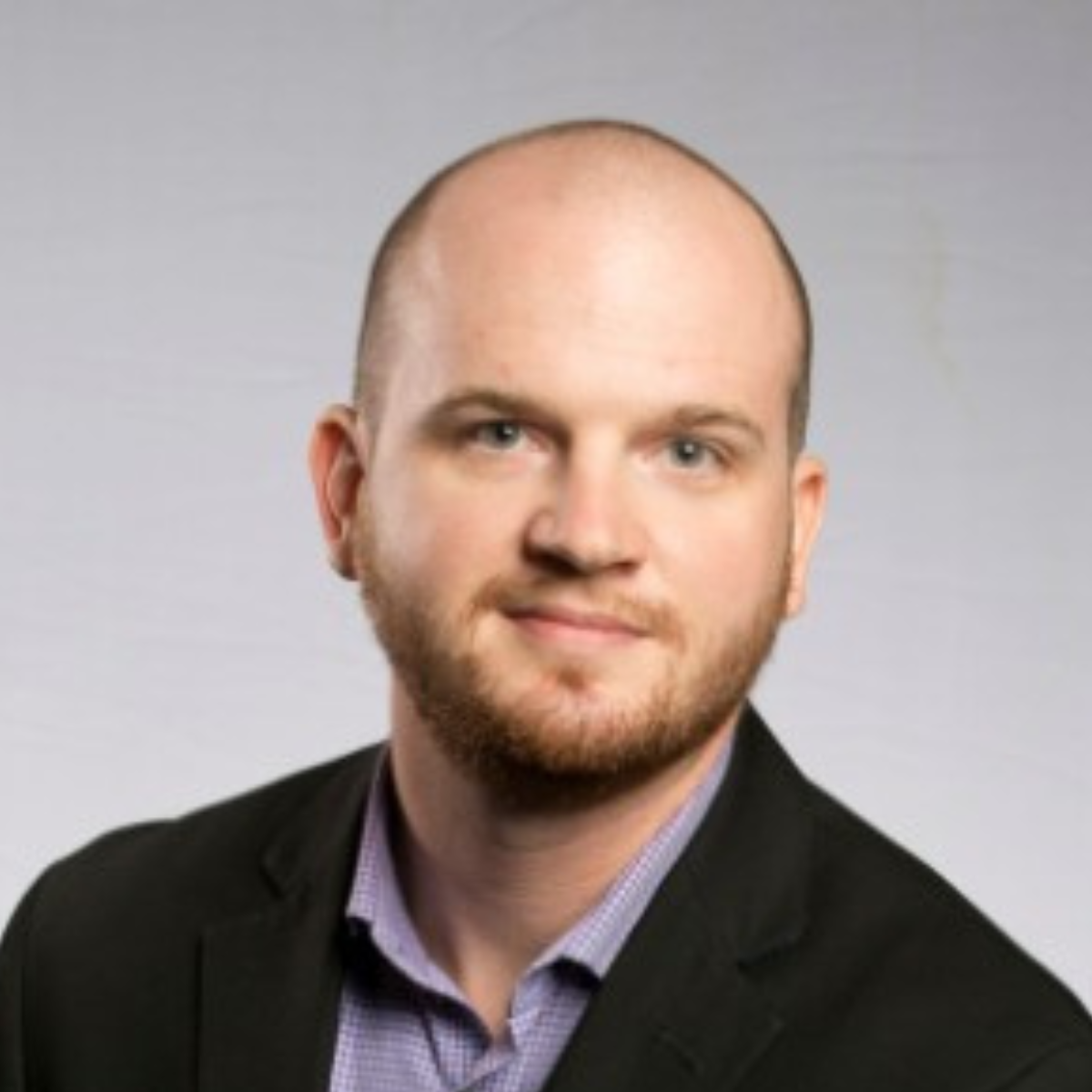 A bald man with a beard wearing a suit and a purple shirt