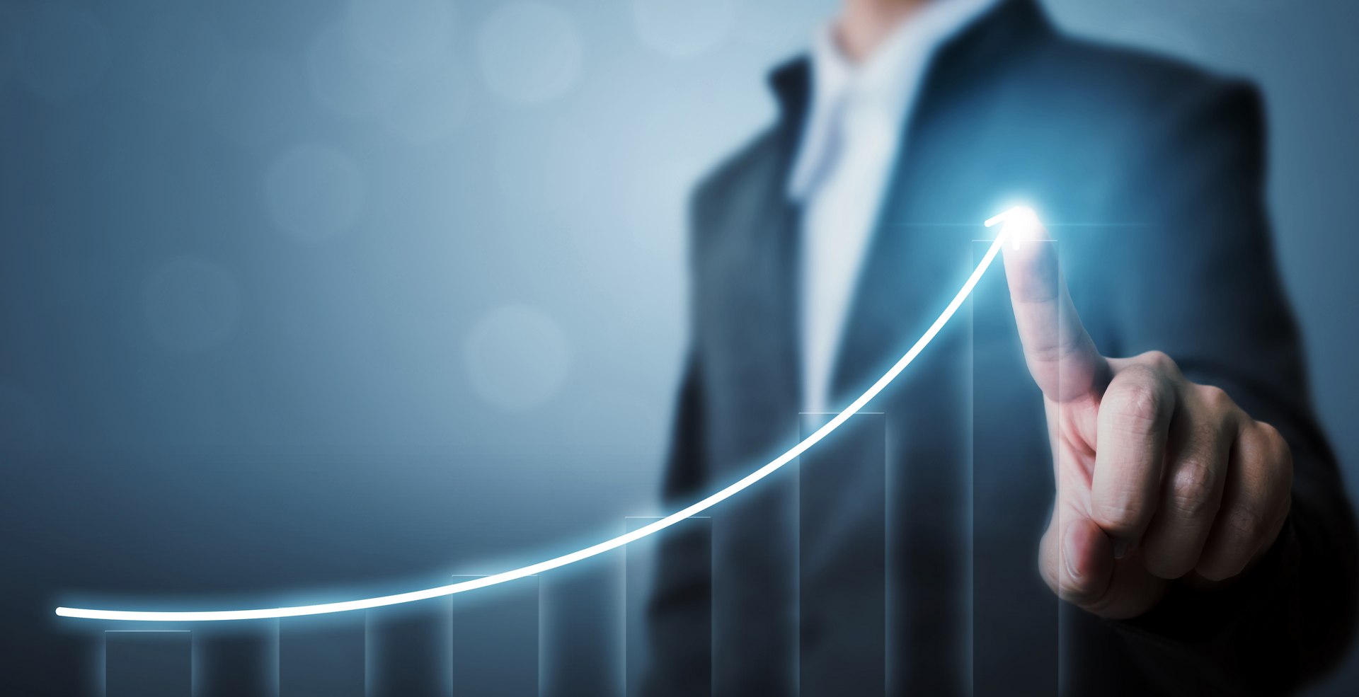 A man in a suit is pointing at a graph that is going up.