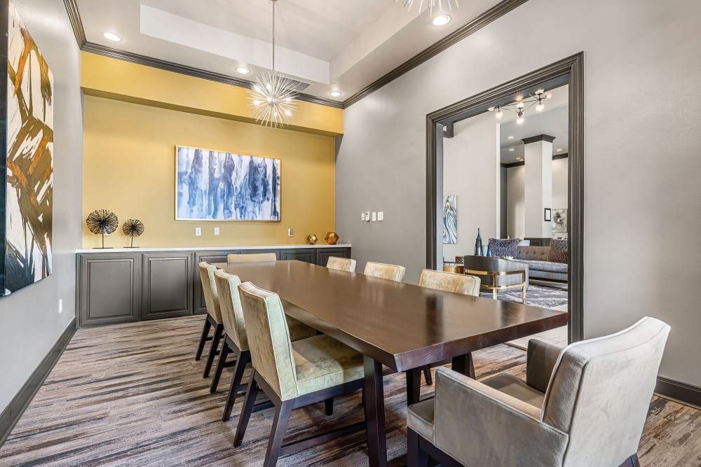 Modern dining room featuring a long wooden table with a combination of bench and chair seating, accented by light grey upholstered chairs at Marquis at Stonebriar in Frisco, TX.