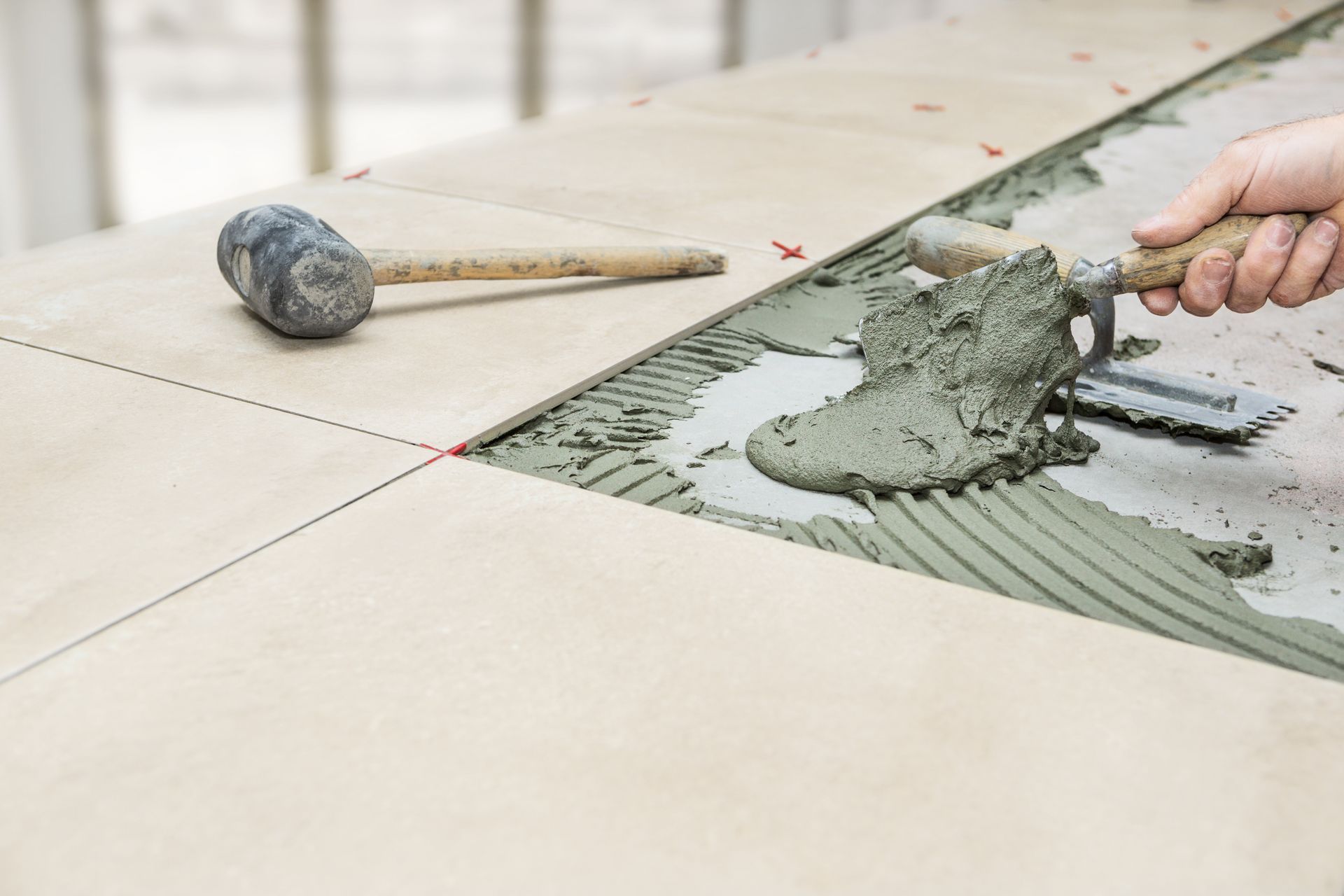 Handyman carefully installing floor tiles in a room, ensuring precise alignment and leveling for a professional finish.