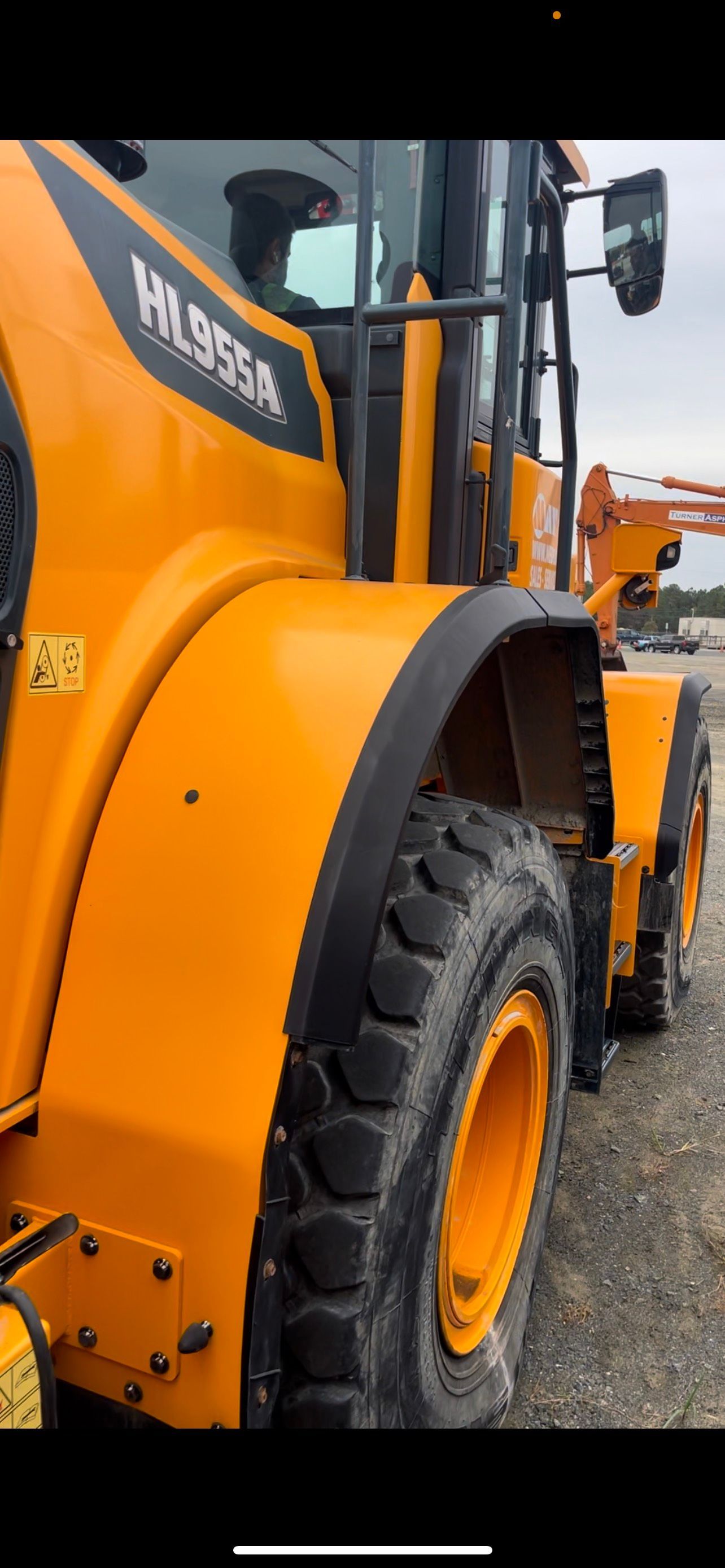 A yellow tractor is parked on a dirt road.