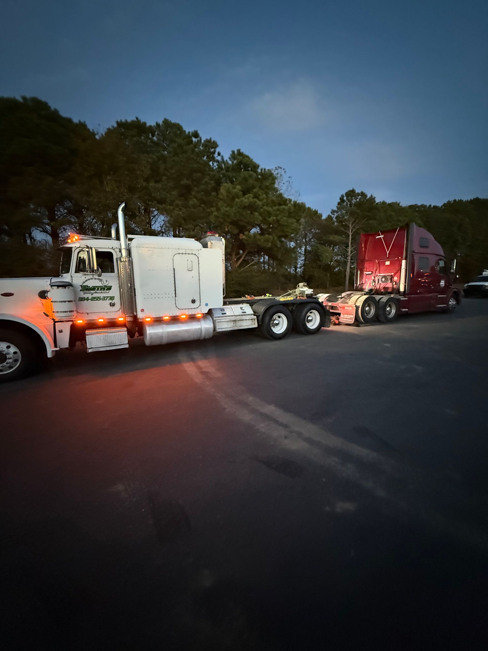 A truck is carrying two tractors down a highway.