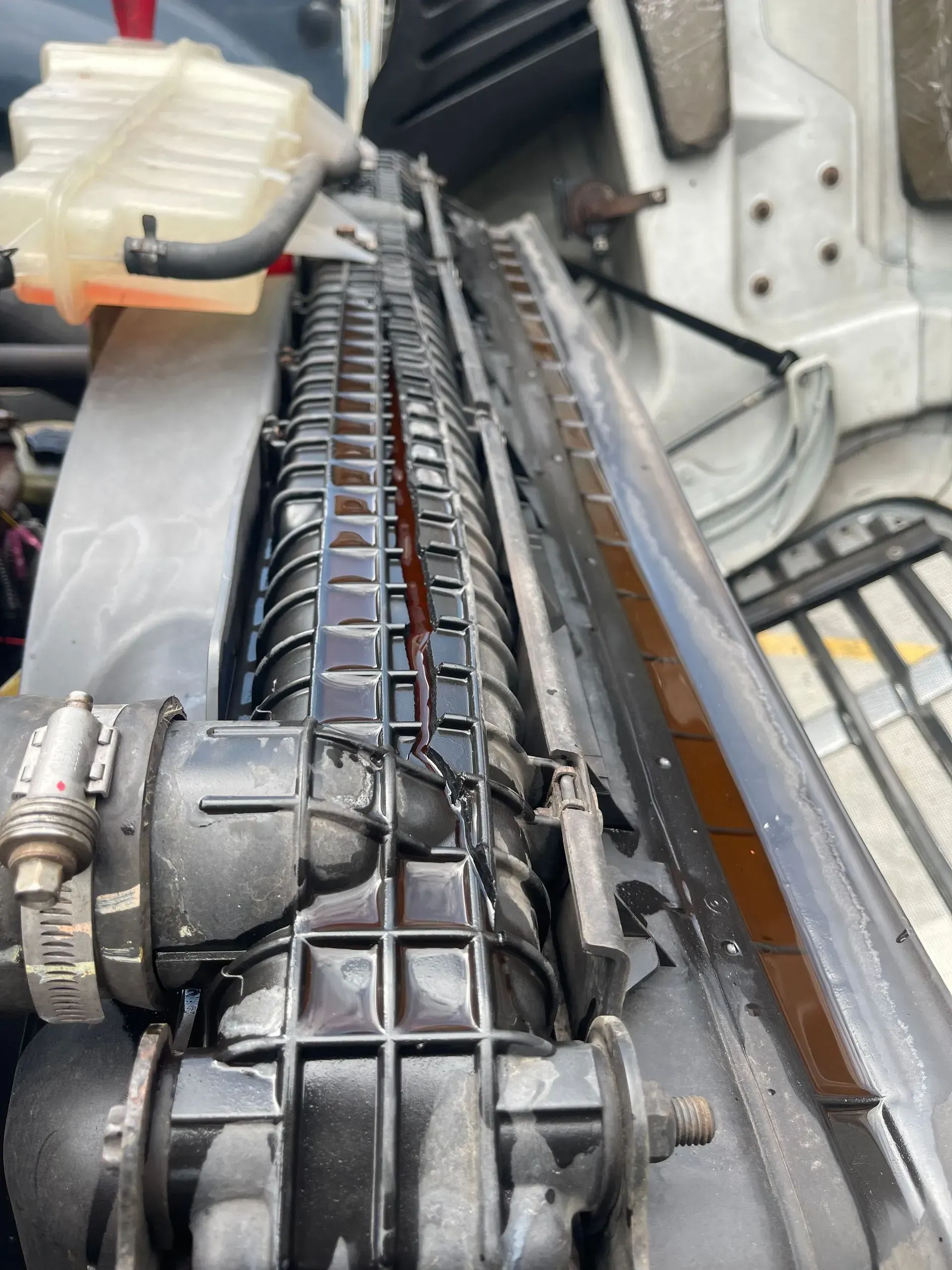 A close up of a radiator on a car with red liquid coming out of it.