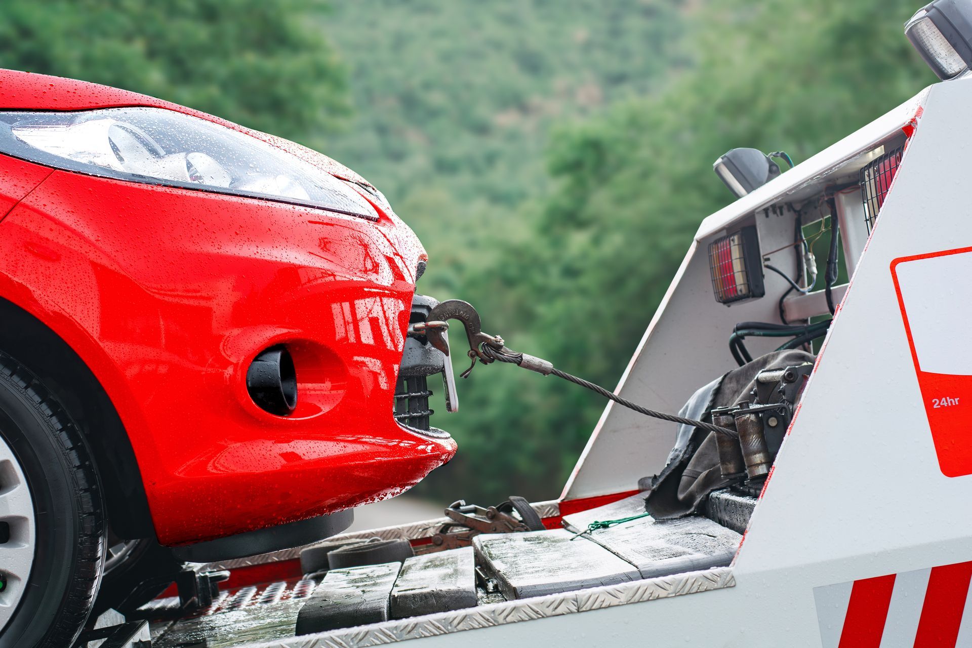 A red car is being towed by a tow truck.