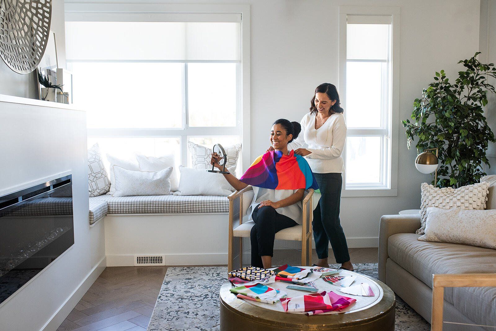 A woman is getting her hair done in a living room by a hairdresser.