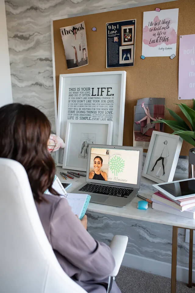 A woman is sitting at a desk using a laptop computer.