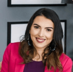 A woman in a pink jacket and purple shirt is smiling for the camera.
