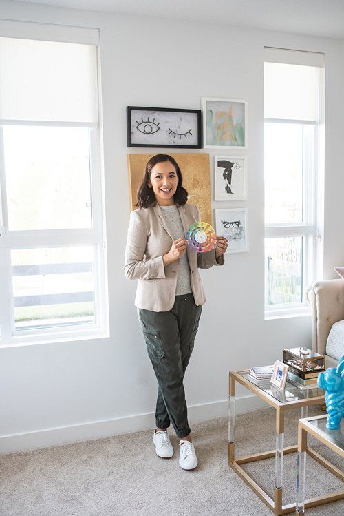 A woman is standing in a living room holding a paint palette.