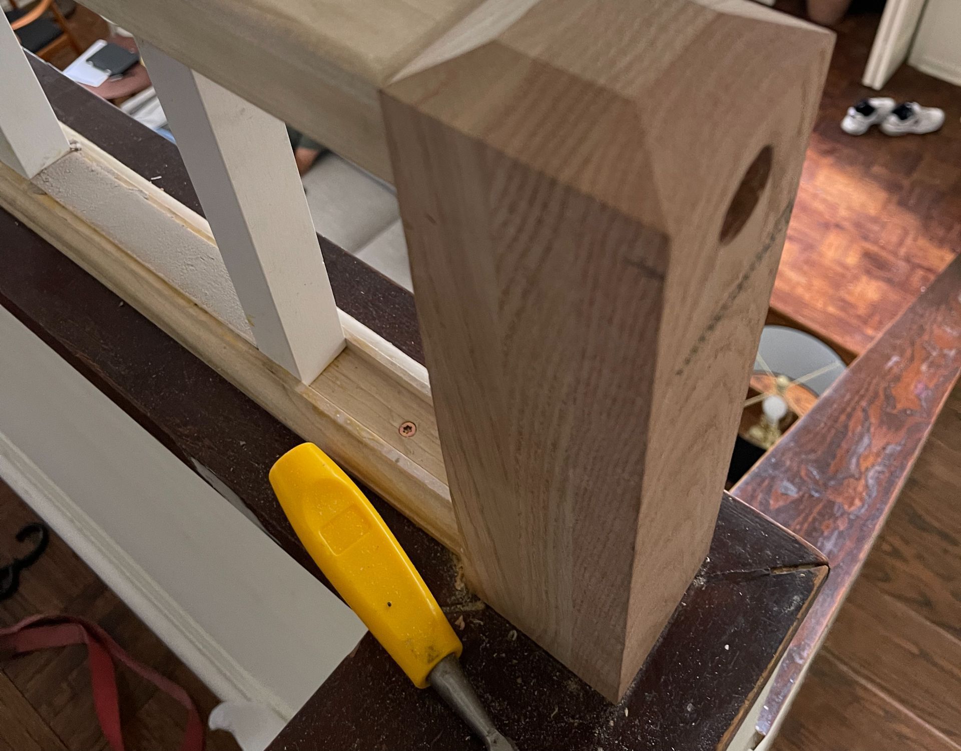 Wooden stair post with chisel and partial railing.