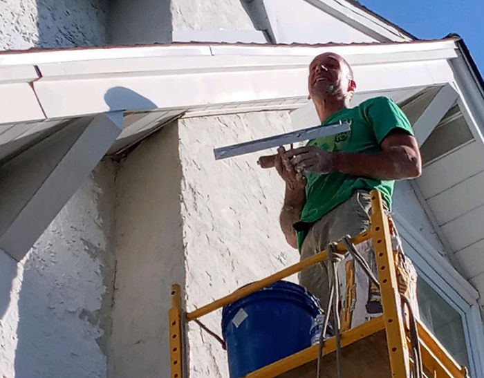 A man in a green shirt is standing on a scaffolding