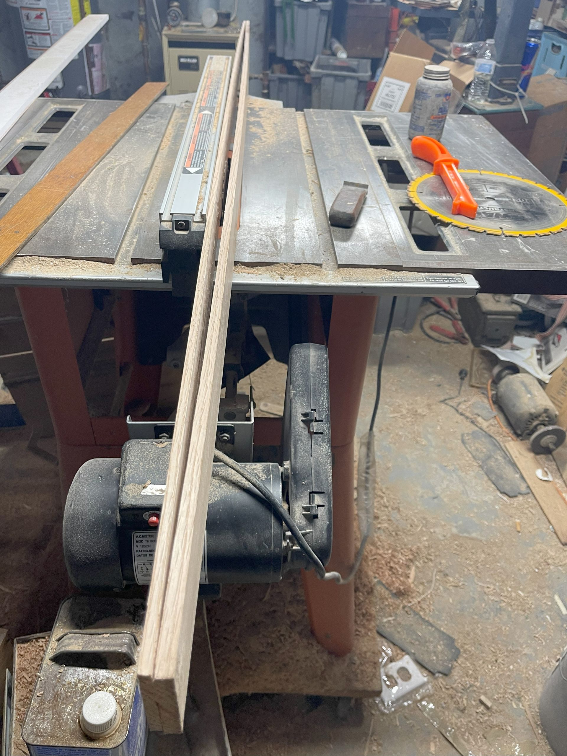 Table saw with wood, fence, and safety guard. Workshop setting.