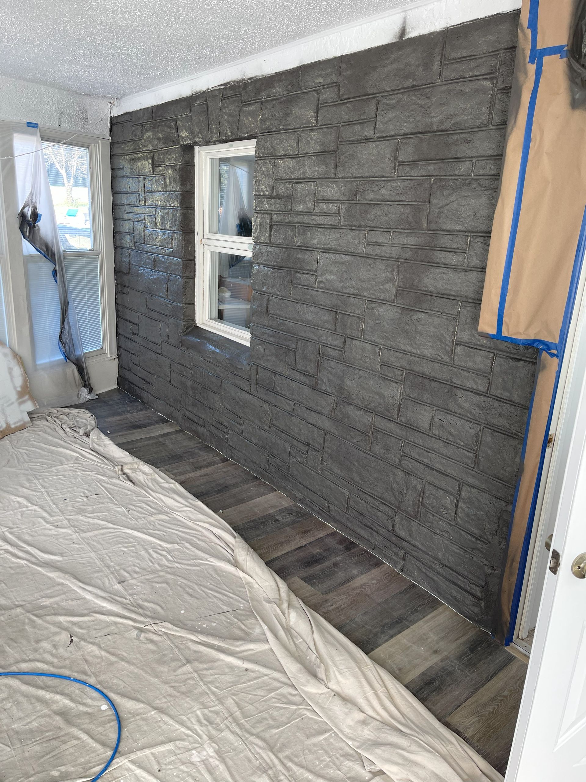 Interior room with gray stone accent wall and wood-look flooring, window visible.