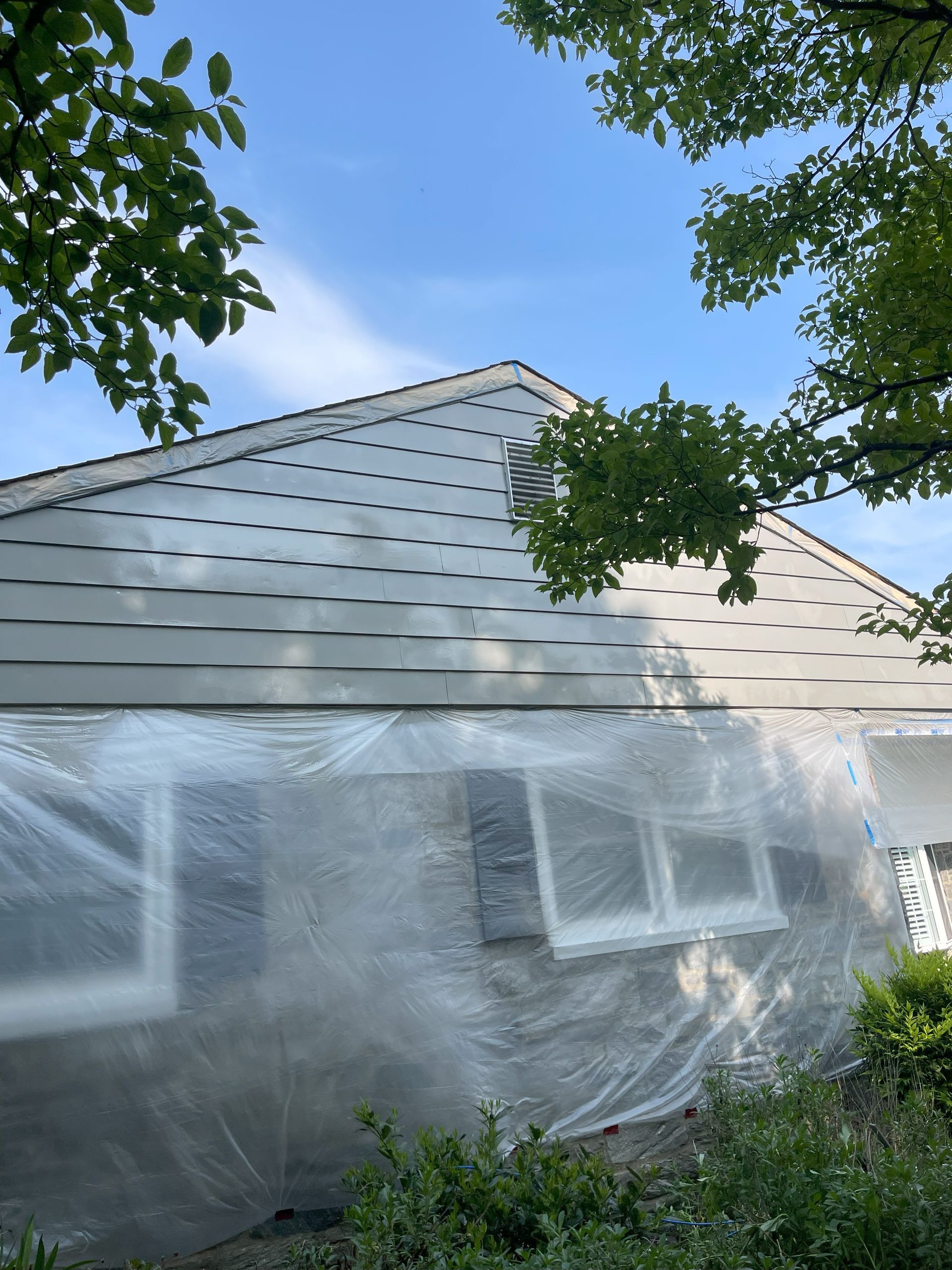 A house is covered in plastic while being painted.
