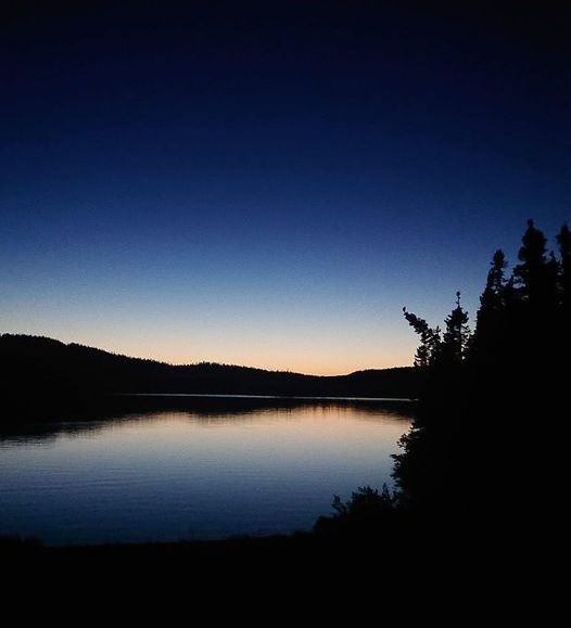 A lake at sunset with trees in the foreground