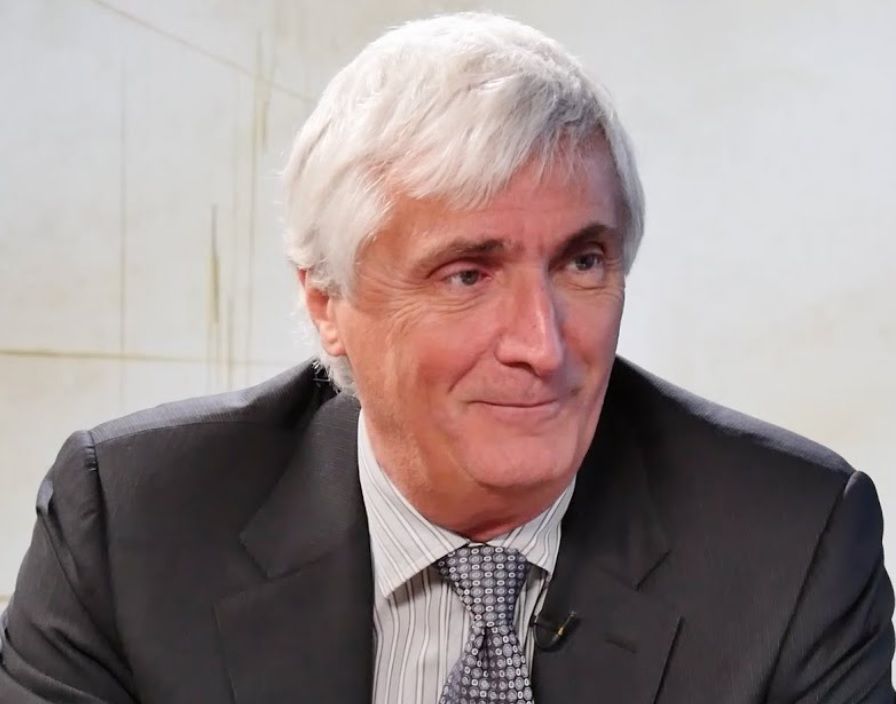 A man with gray hair is wearing a suit and tie