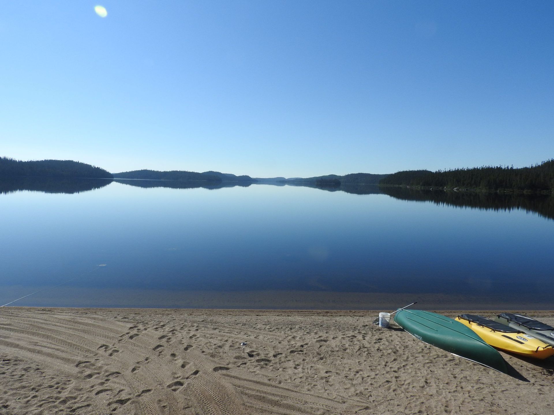 Deux kayaks sont sur la plage près d'un lac