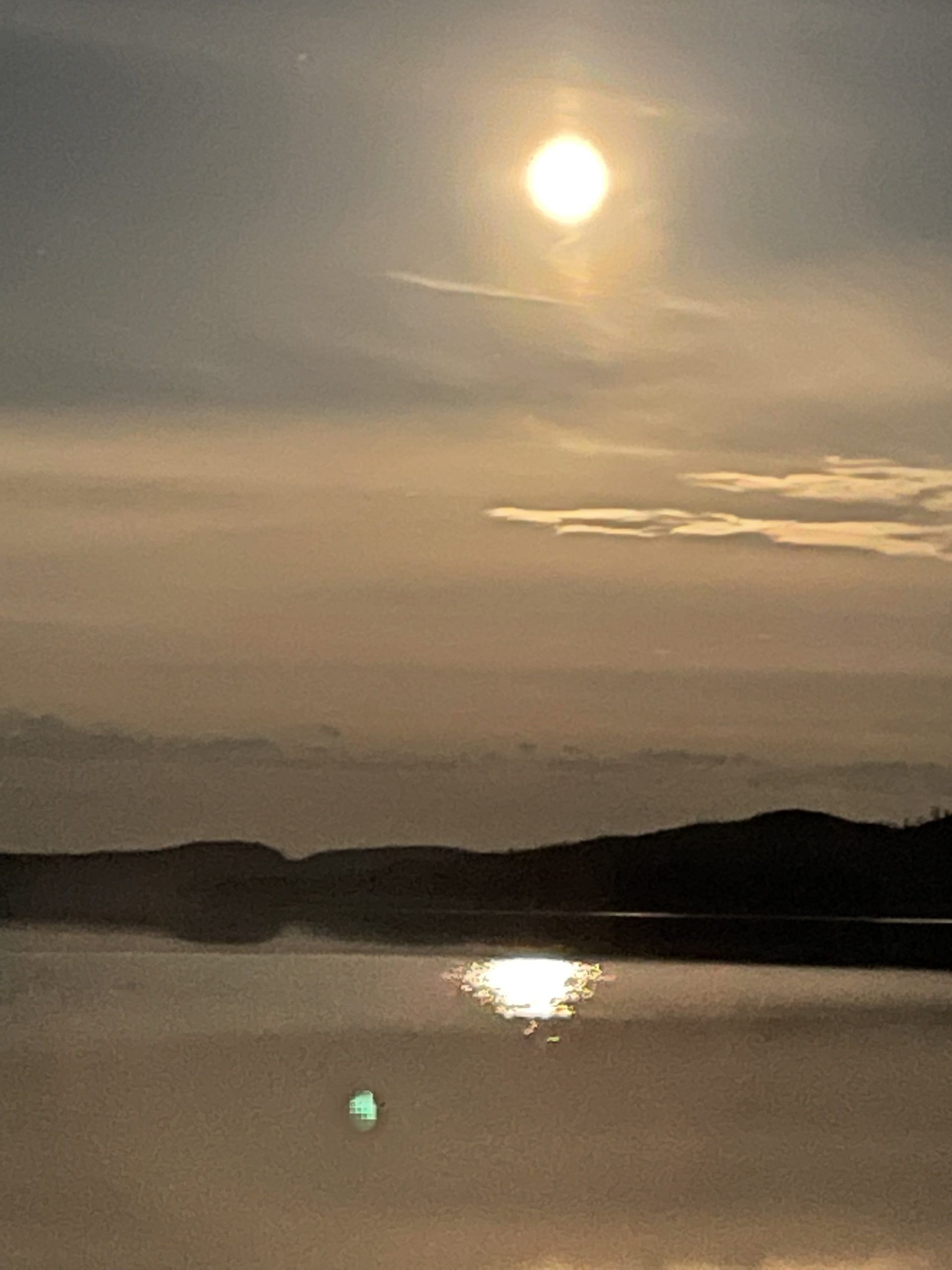 Le soleil se couche sur un lac avec des montagnes en arrière-plan