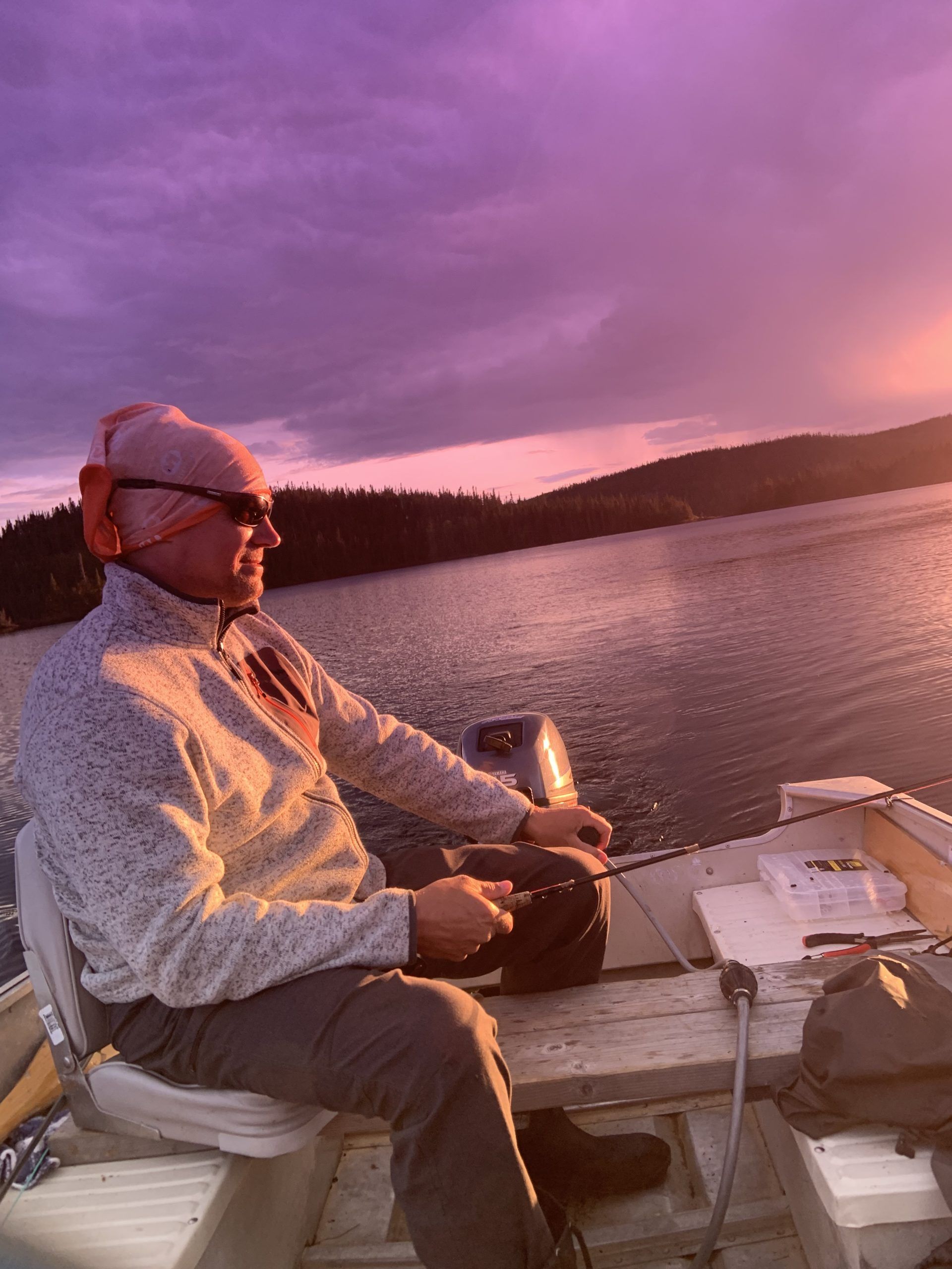 Un homme est assis sur un bateau avec un ciel violet en arrière-plan.