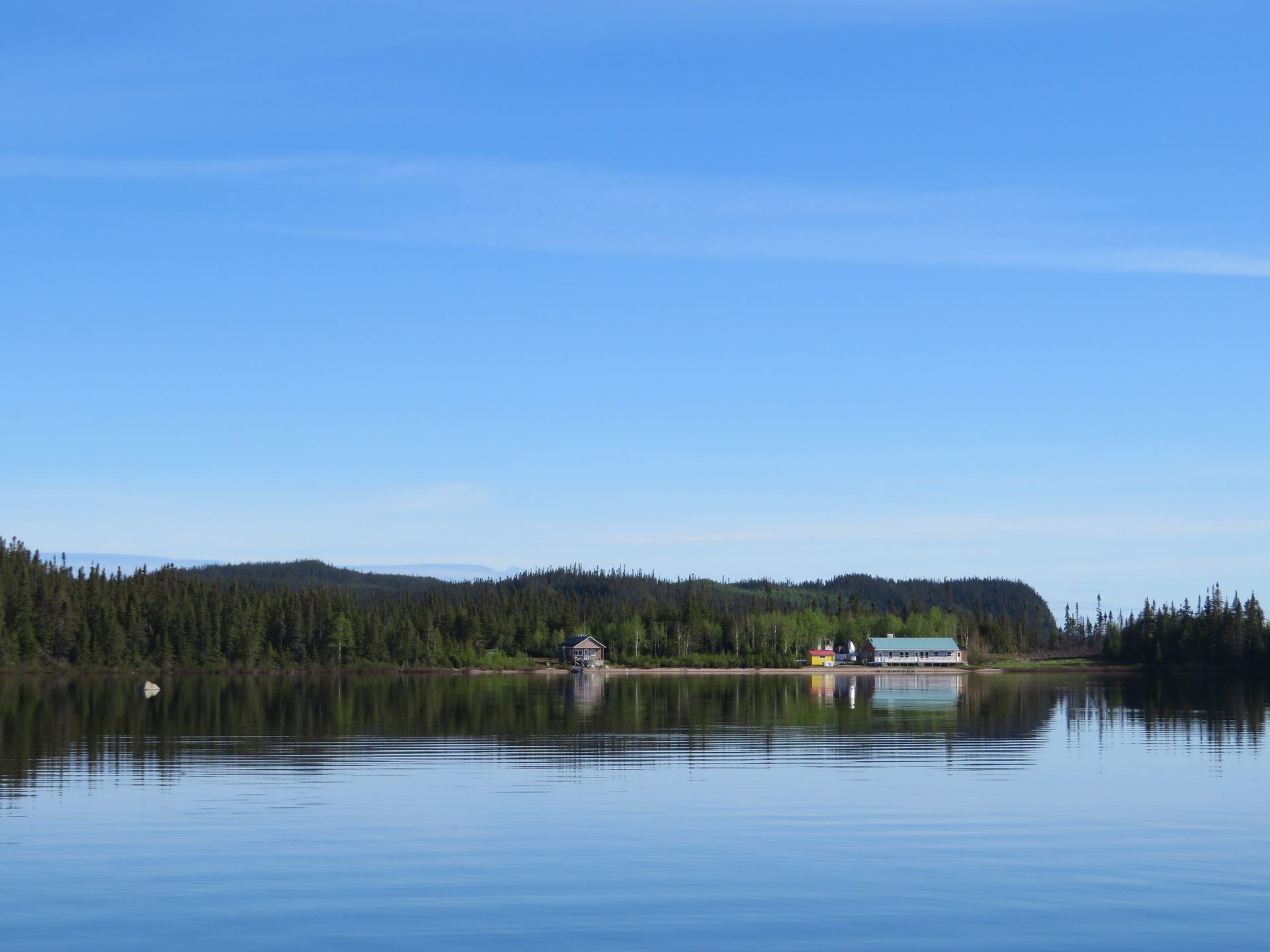 Une maison est située sur la rive d'un lac entouré d'arbres.