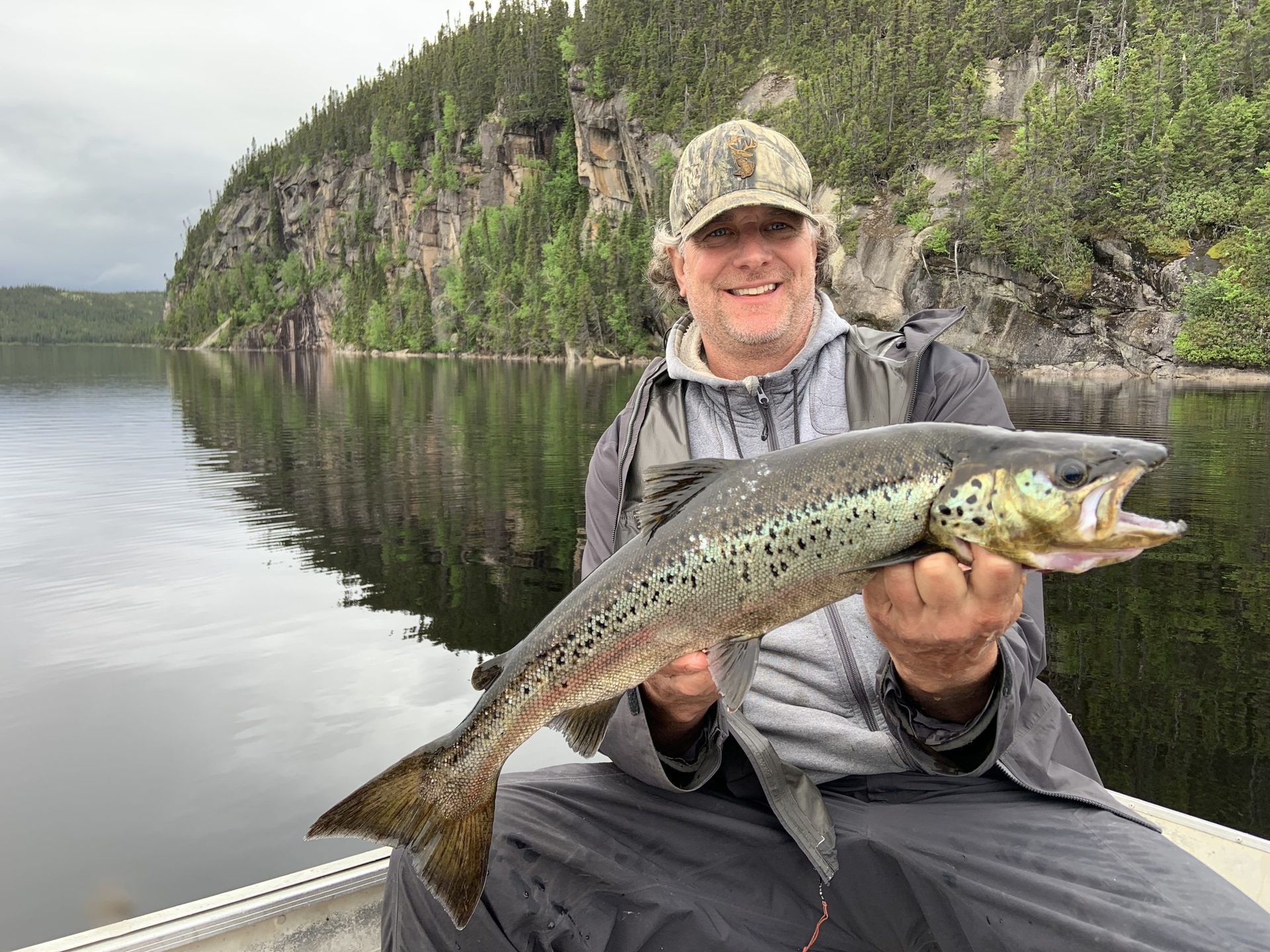 Un homme est assis sur un bateau tenant un gros poisson.