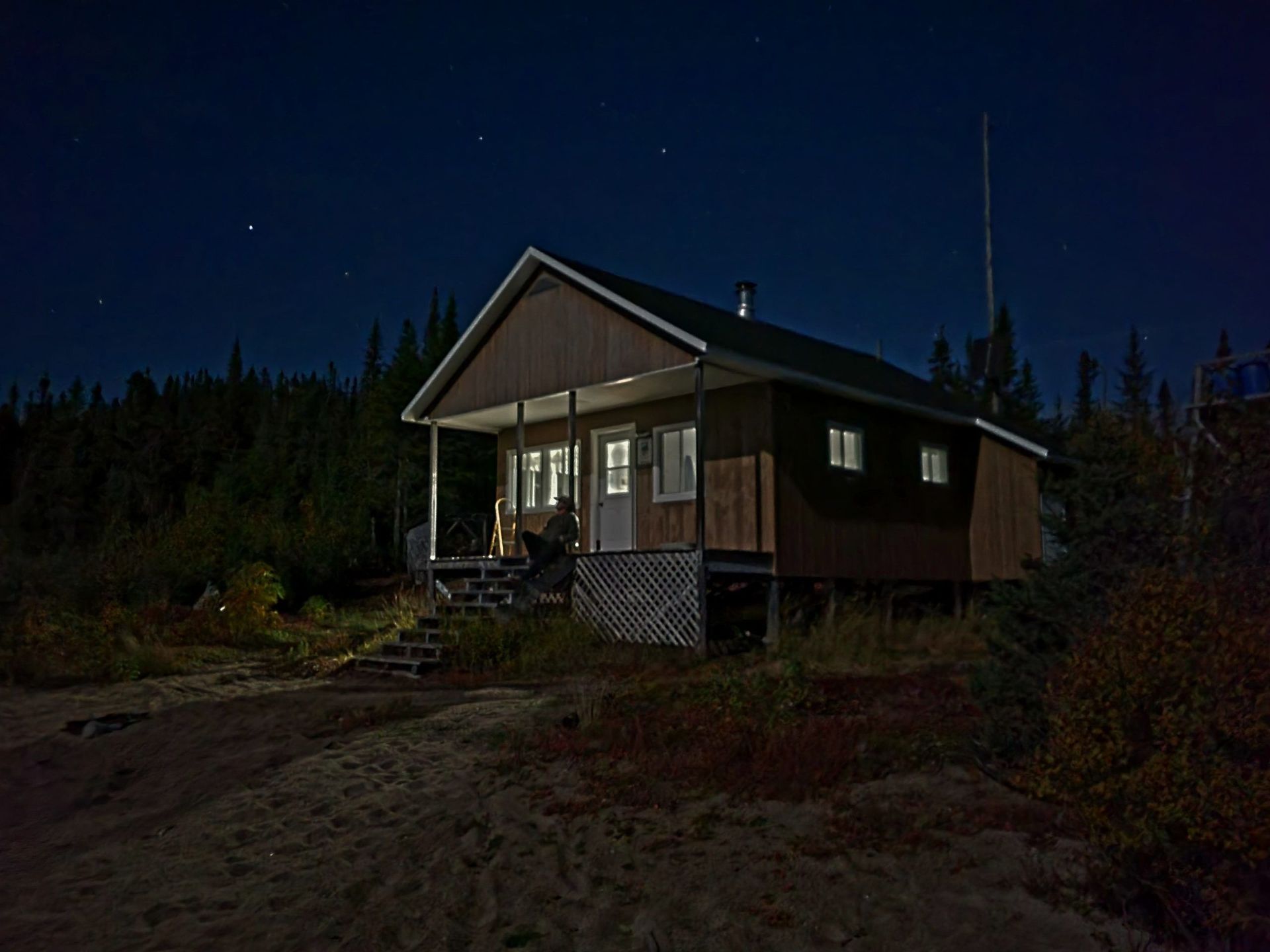 Une petite maison avec un porche est éclairée la nuit