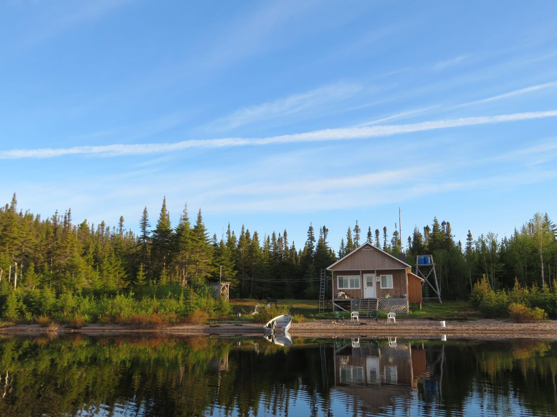 Une petite maison se trouve au bord d'un lac entouré d'arbres